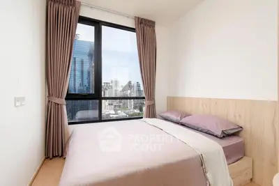 Modern bedroom with city view and large window, featuring elegant curtains and cozy bedding.