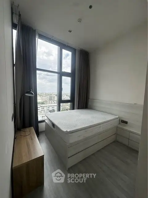 Modern bedroom with large window offering a stunning city view.