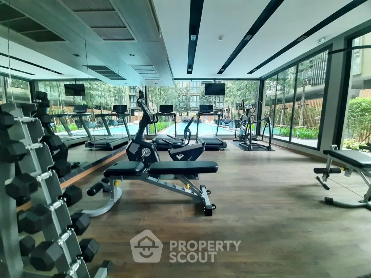 Modern gym with state-of-the-art equipment and pool view in luxury residential complex.