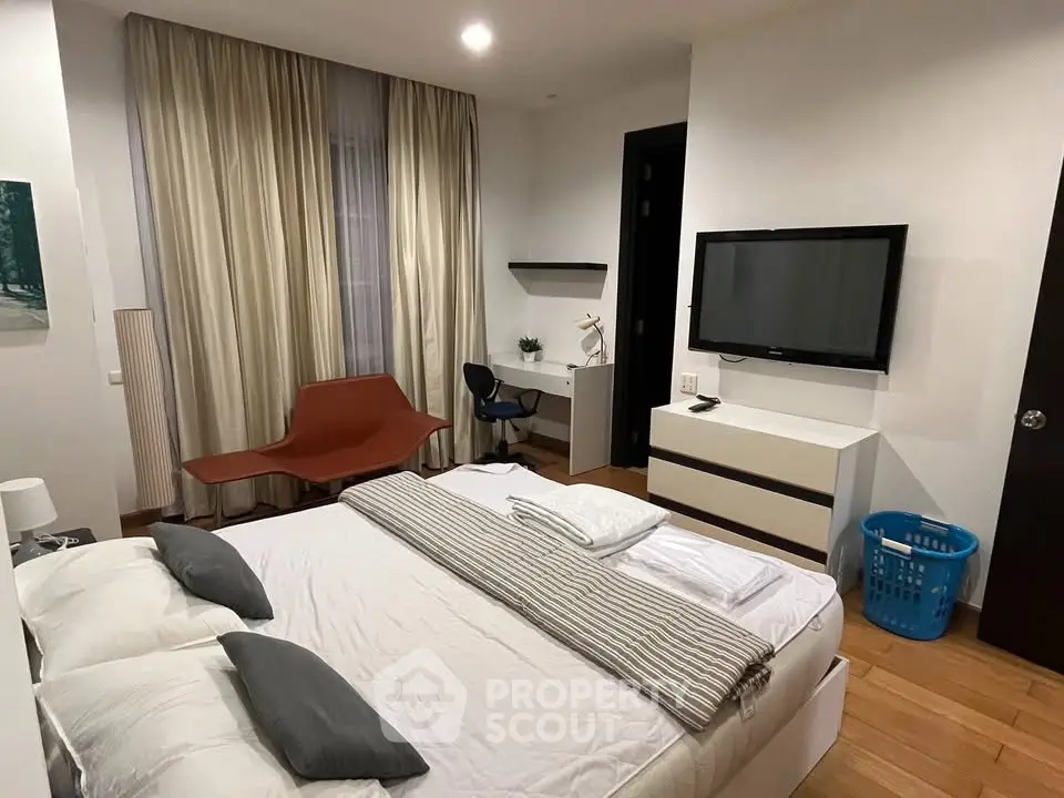 Spacious modern bedroom with stylish decor and cozy ambiance, featuring a large bed and wall-mounted TV.