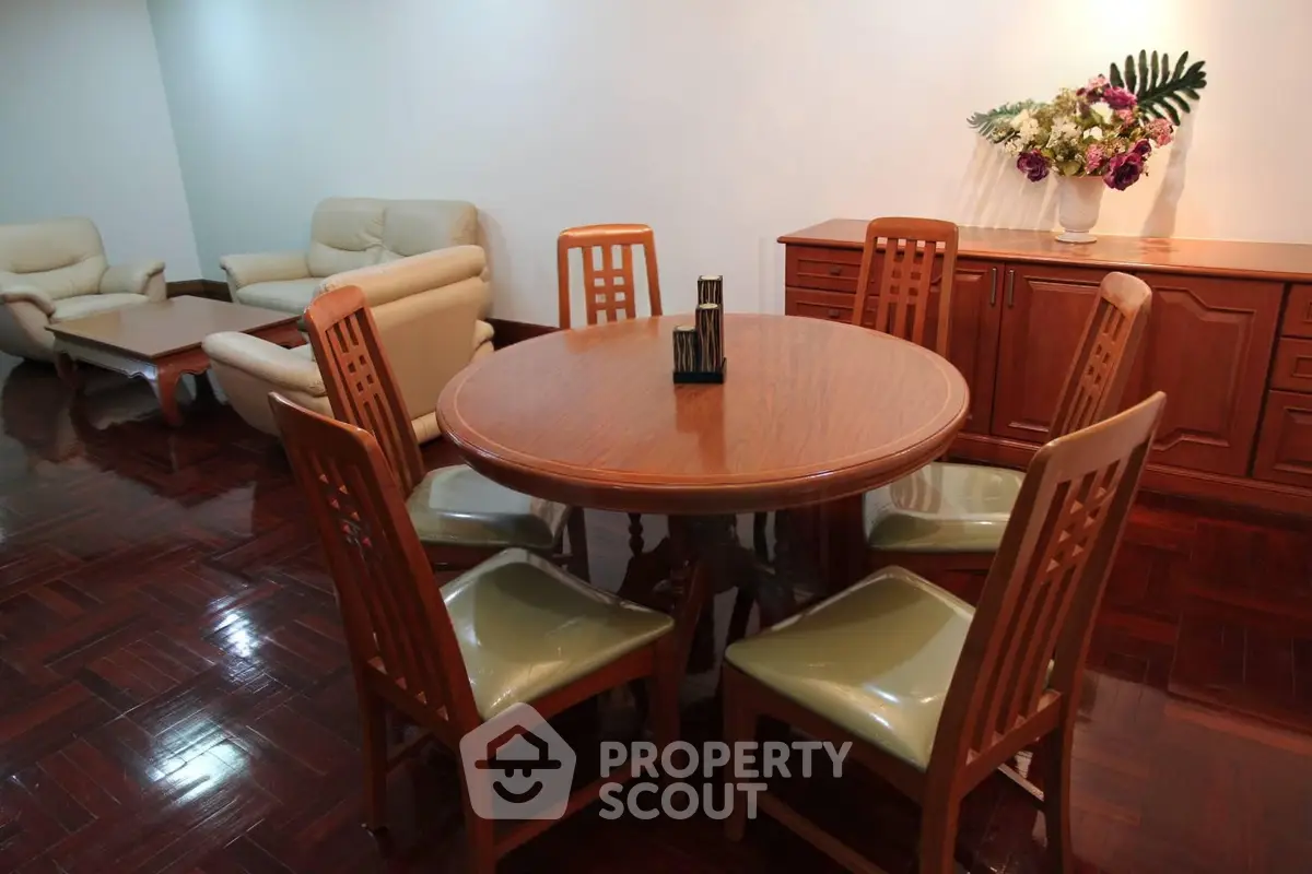 Spacious living room with elegant wooden dining set and cozy seating area.