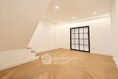 Spacious modern living room with elegant wooden flooring and stylish glass door.