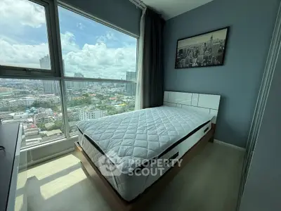 Modern bedroom with large window offering stunning city views, featuring a comfortable bed and stylish decor.