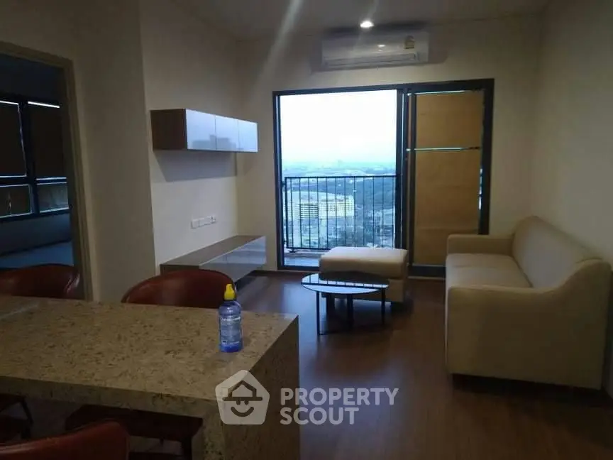 Modern living room with balcony view, featuring sleek furniture and air conditioning.