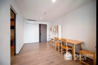 Spacious modern living room with sleek wooden flooring, minimalist furniture, and ample natural light, perfect for urban living.