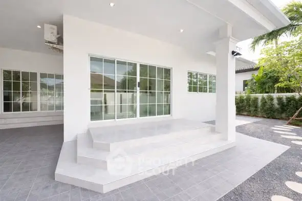 Modern white exterior with sliding glass doors and tiled steps
