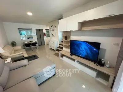 Modern living room with sleek furniture and large TV, perfect for relaxation and entertainment.