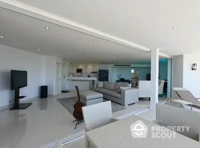 Expansive open-plan living space with sleek white tiles, modern furniture, and abundant natural light, perfect for entertaining and relaxation.