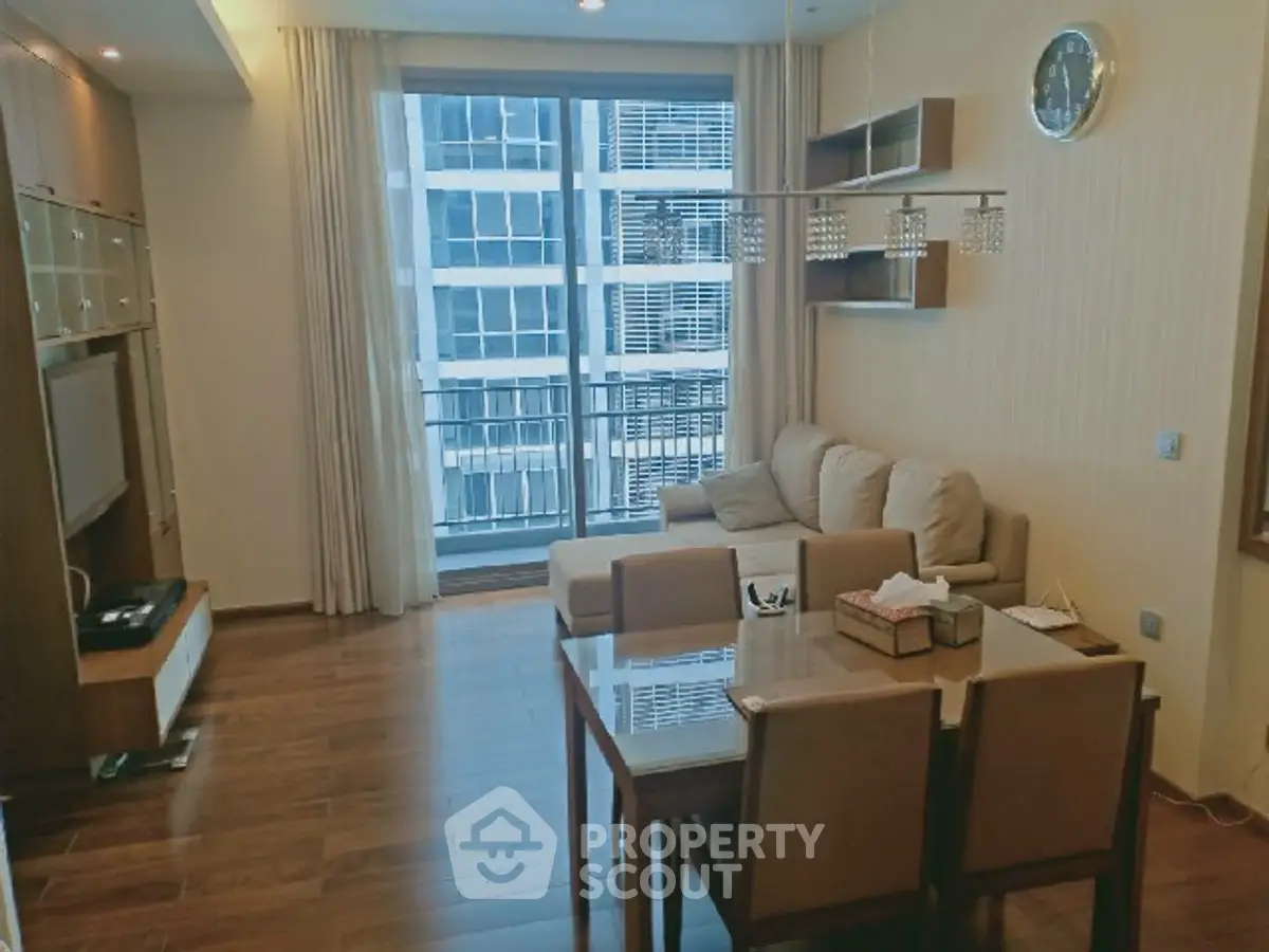 Modern living room with wooden flooring, cozy sofa, and large window offering city view.