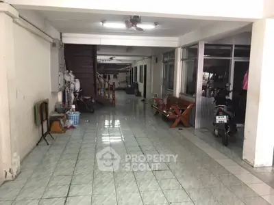 Spacious tiled garage area with staircase and seating, ideal for storage or parking.