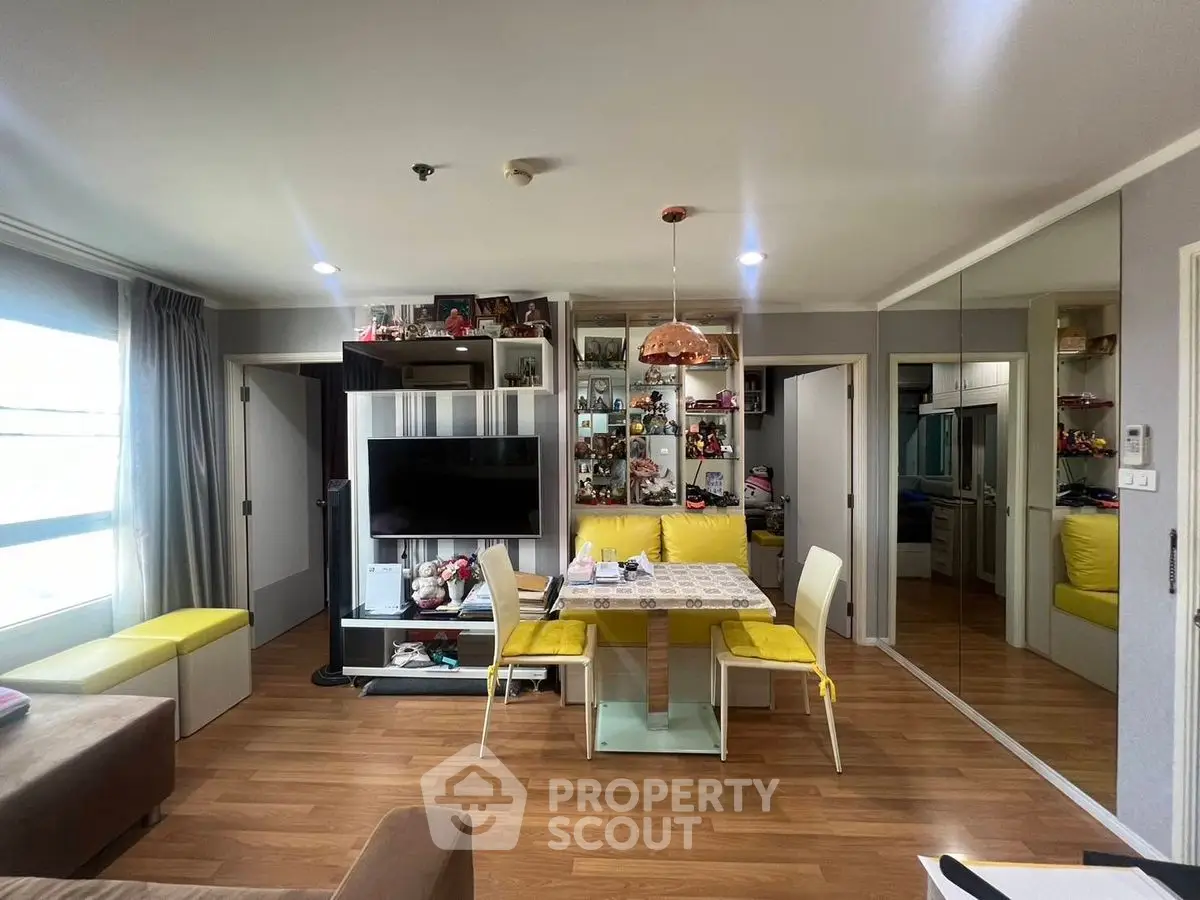Modern living room with stylish decor, large TV, and dining area in open layout apartment.