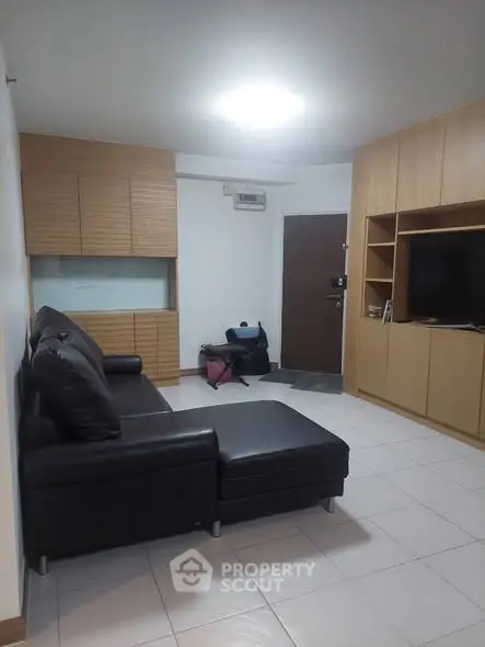 Modern living room with sleek black sofa and built-in wooden cabinets, perfect for stylish urban living.