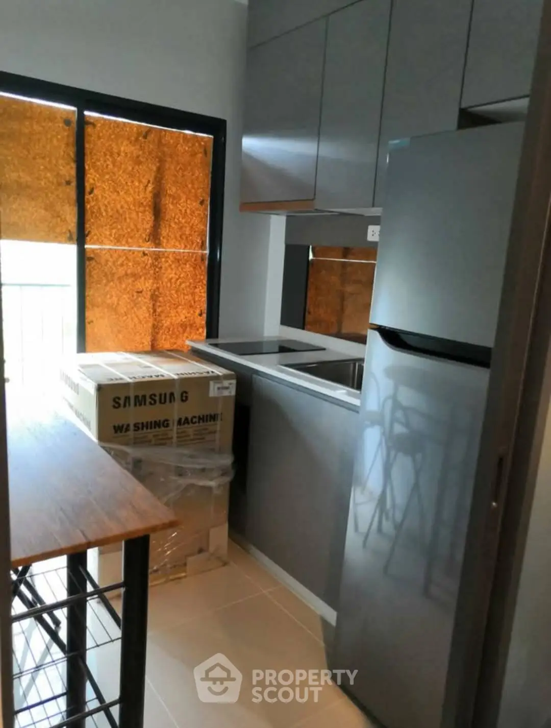 Modern kitchen with sleek cabinets and new appliances, featuring a Samsung washing machine and stainless steel fridge.