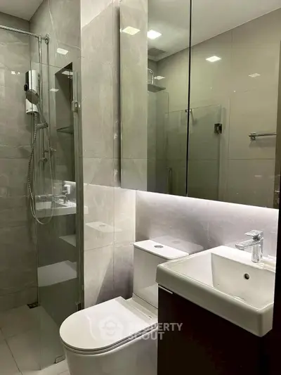 Modern bathroom with glass shower and sleek fixtures in a contemporary apartment.