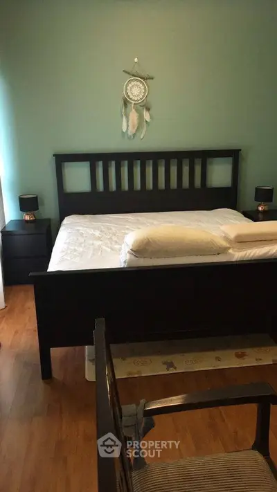 Cozy bedroom with wooden bed frame and dreamcatcher decor, perfect for relaxation.