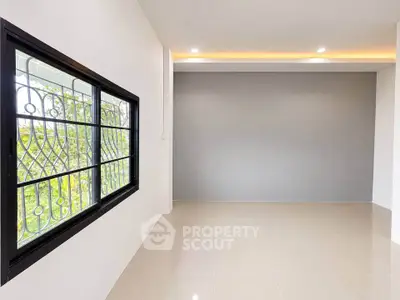 Spacious empty room with large window and modern tile flooring, perfect for customization.