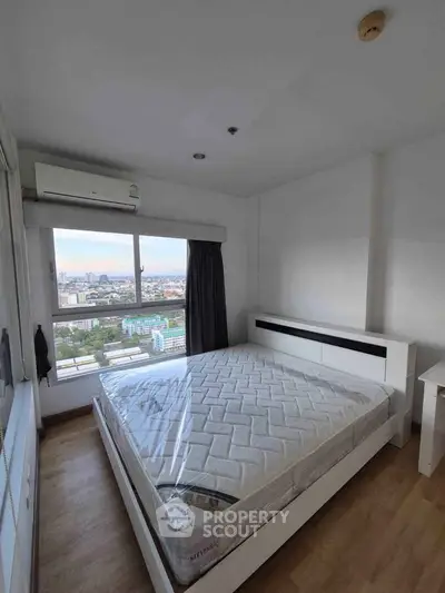 Spacious bedroom with city view and modern furnishings in high-rise apartment.