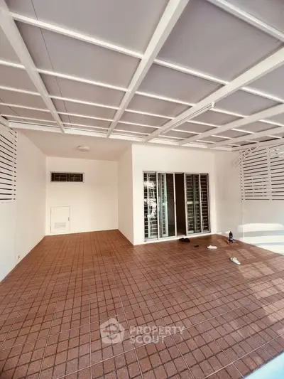 Spacious covered patio with tiled flooring and sliding glass doors, perfect for outdoor relaxation.