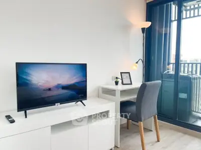 Modern living room with TV, desk, and balcony access in a stylish apartment.