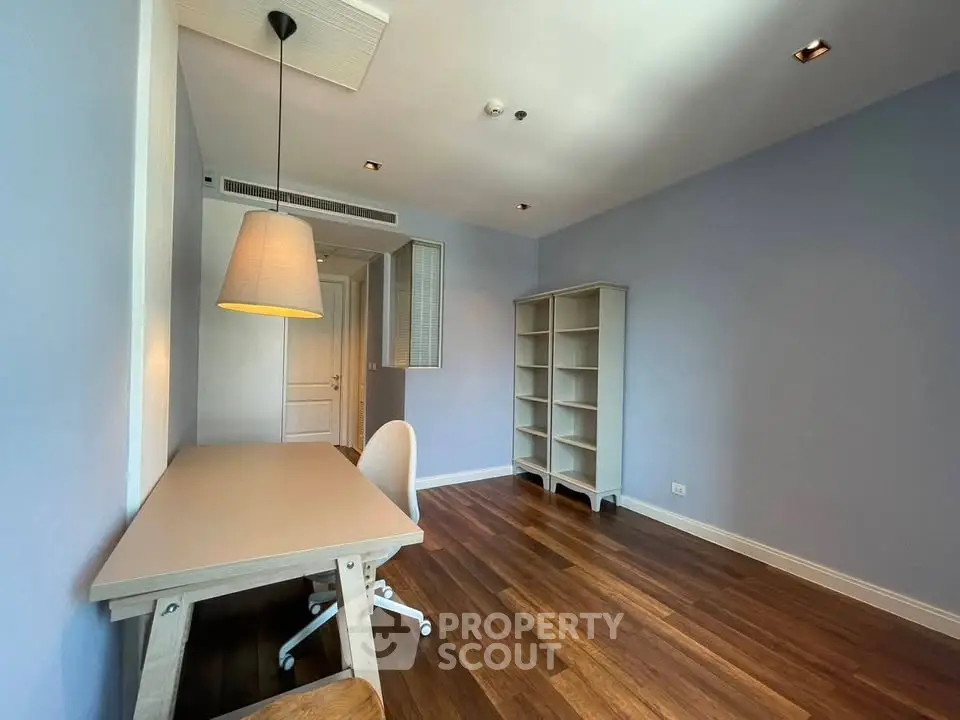 Spacious study room with wooden flooring and modern furniture in a bright apartment.