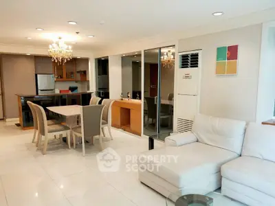 Spacious open-plan living and dining area with modern kitchen and elegant chandelier.