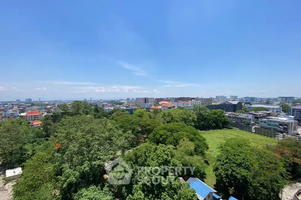 Stunning panoramic cityscape view with lush greenery and urban skyline under clear blue sky.
