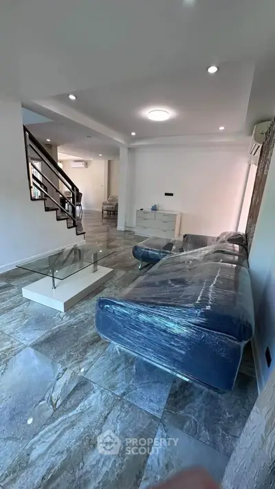 Spacious modern living room with sleek tiled flooring and elegant staircase