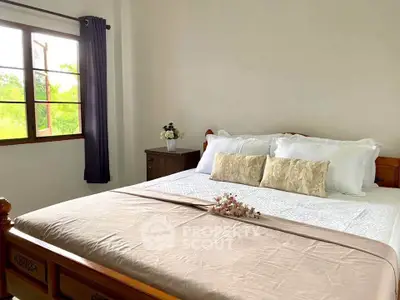 Cozy bedroom with large window and elegant decor, perfect for relaxation and comfort.