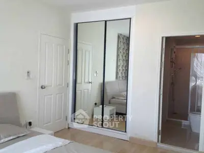 Modern bedroom with mirrored wardrobe and ensuite bathroom in a stylish apartment.