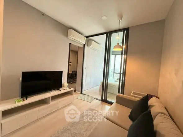Modern living room with sleek design and glass partition leading to bedroom