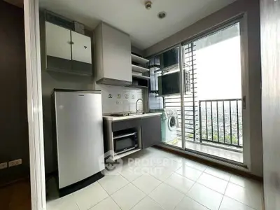 Compact kitchen with balcony view and modern appliances in urban apartment.