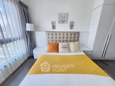 Modern bedroom with stylish decor and large window offering city views