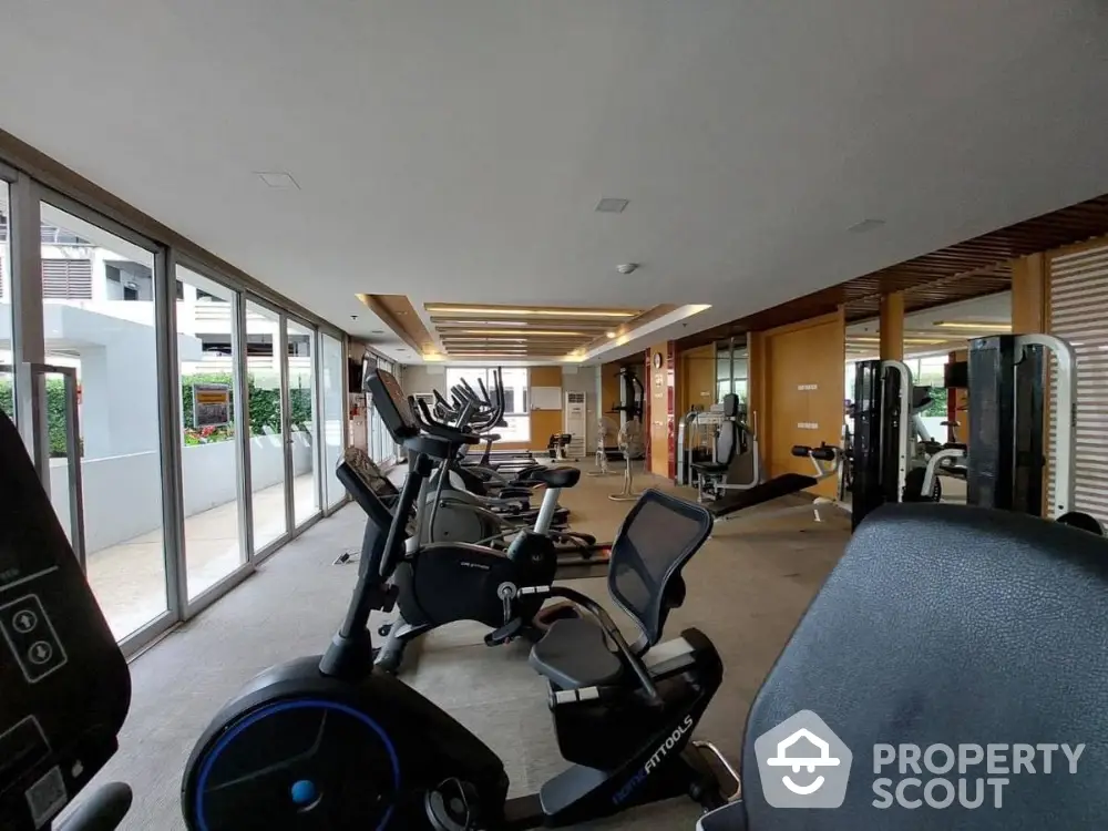 Spacious modern gym with state-of-the-art fitness equipment and large windows for natural light.