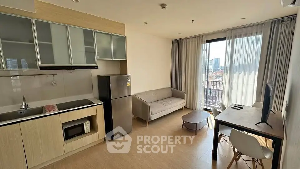 Modern open-layout living room with kitchen, featuring sleek furniture and city view balcony.