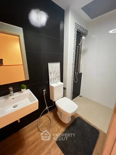 Modern bathroom with sleek black and white tiles, featuring a stylish sink and shower area.