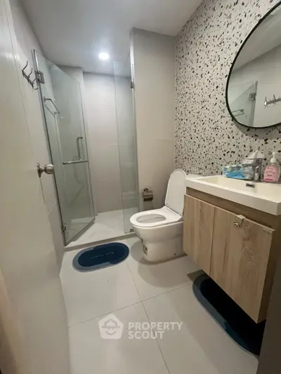 Modern bathroom with glass shower and stylish vanity in contemporary apartment.