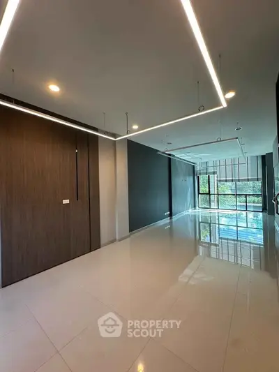 Spacious modern living room with sleek lighting and large windows offering natural light.