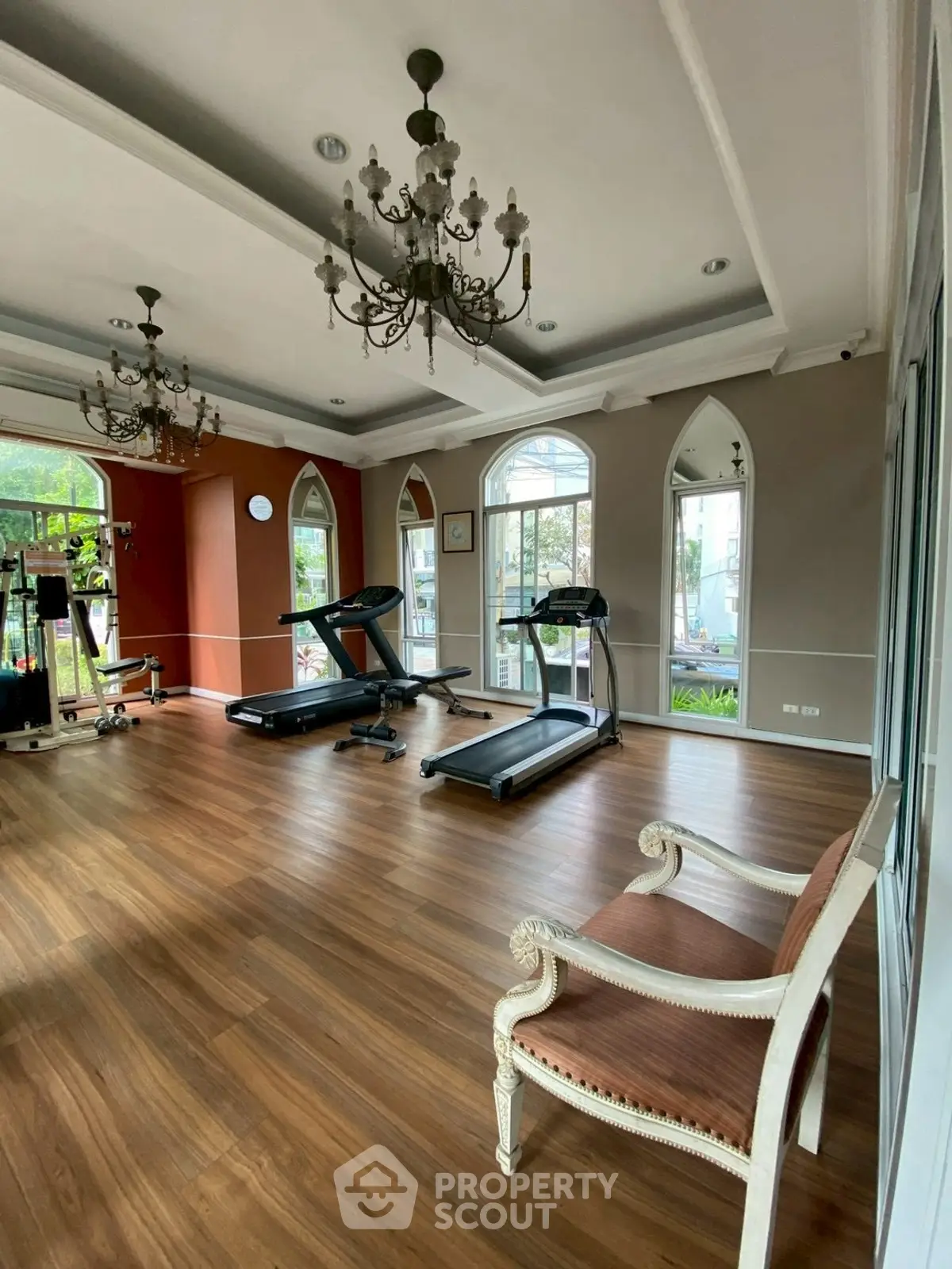 Luxurious gym with elegant chandeliers and modern equipment in a stylish real estate property.