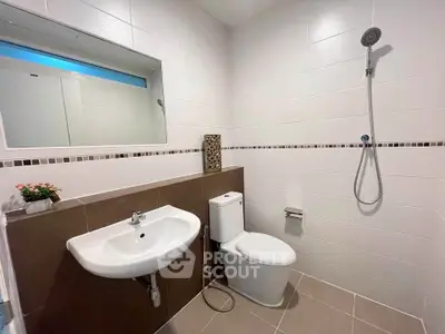Modern bathroom with sleek fixtures and minimalist design, featuring a shower and elegant sink.