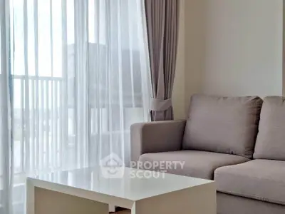 Modern living room with cozy sofa and natural light through sheer curtains.