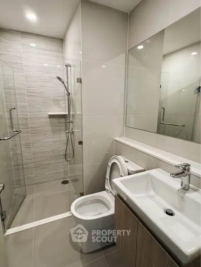 Modern bathroom with sleek design, glass shower, and elegant fixtures in a contemporary apartment.