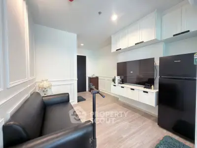 Modern living room with sleek black sofa, wall-mounted TV, and contemporary decor.