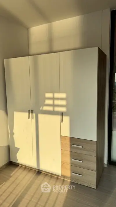 Modern wardrobe in a sunlit room with sleek design and ample storage space.