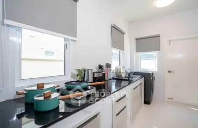Modern kitchen with sleek countertops and appliances, featuring a washing machine and stylish cookware.