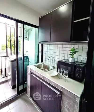 Modern compact kitchen with sleek cabinetry and balcony view