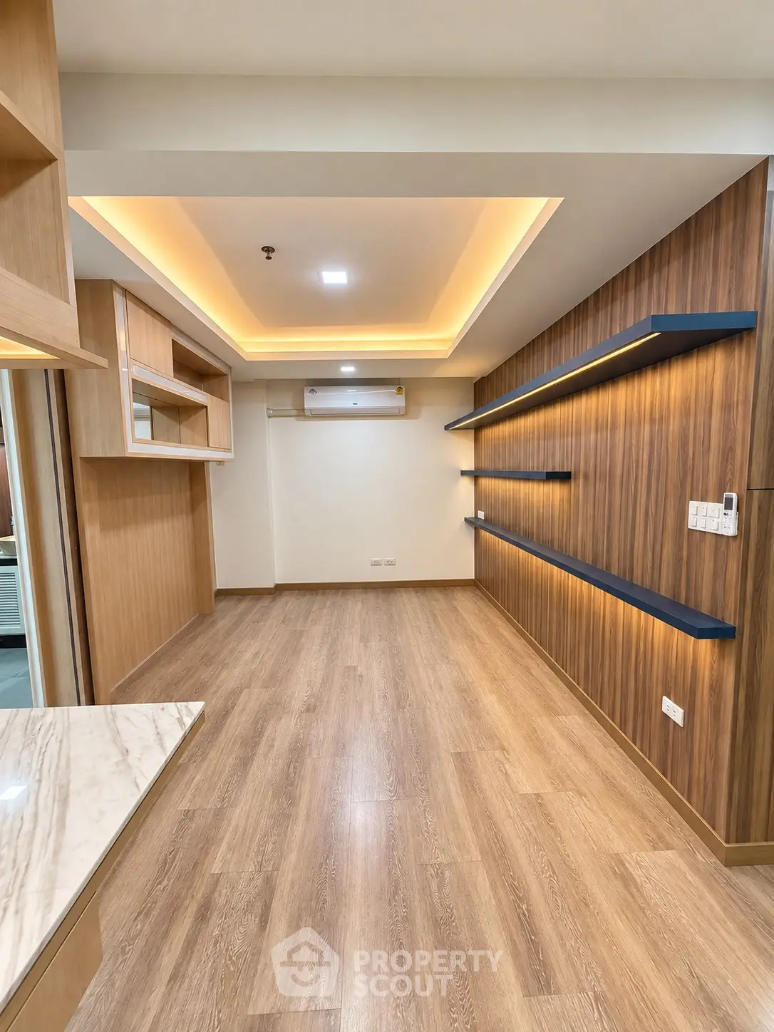 Modern living room with wooden flooring and sleek wall shelves in a stylish apartment.