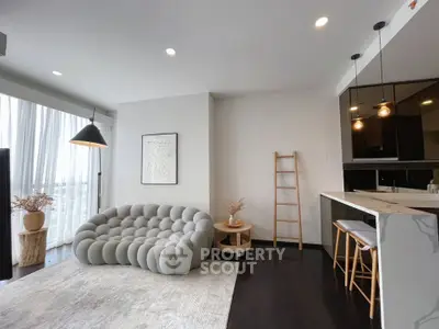 Modern living room with stylish sofa and open kitchen layout in a bright apartment.