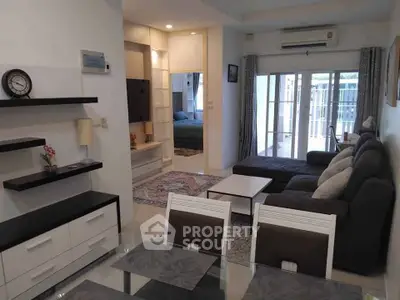 Modern living room with stylish furniture and open layout leading to a cozy bedroom.