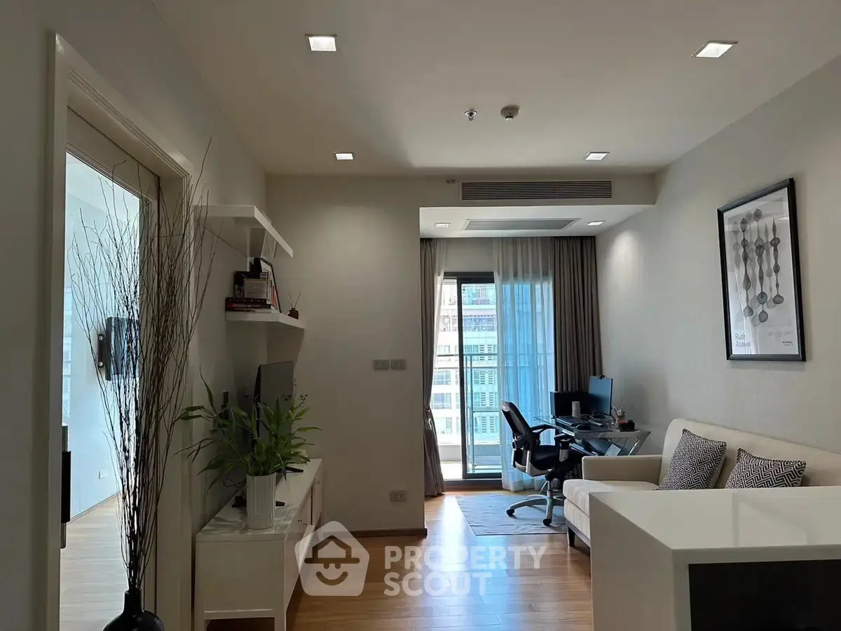 Modern living room with home office setup and balcony view in a stylish apartment.