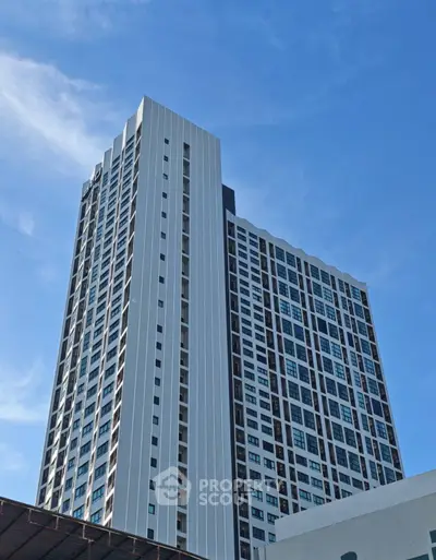 Modern high-rise building with sleek design against a clear blue sky.